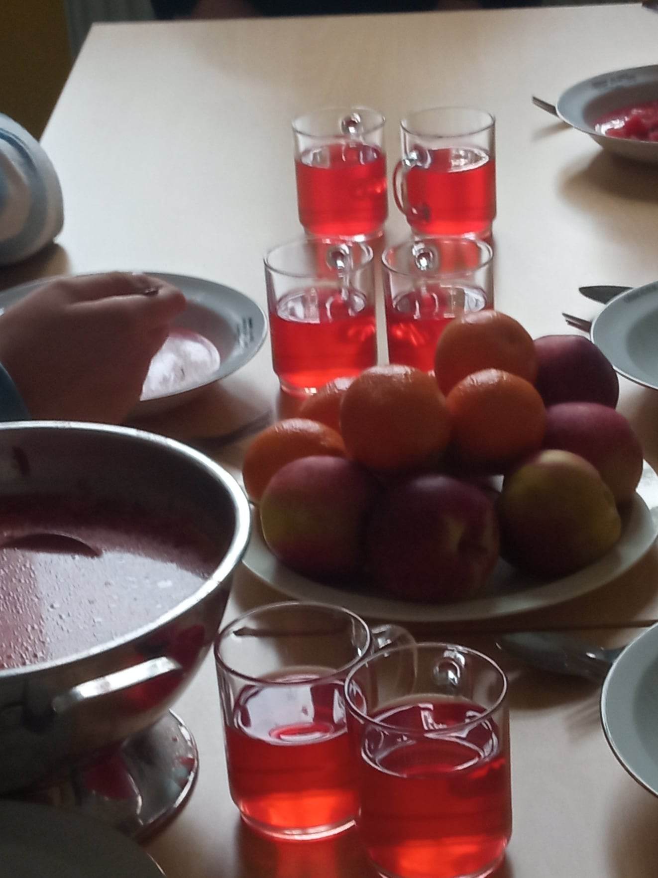 Na stole stoją talerze i szklanki  z potrawami i napojami
