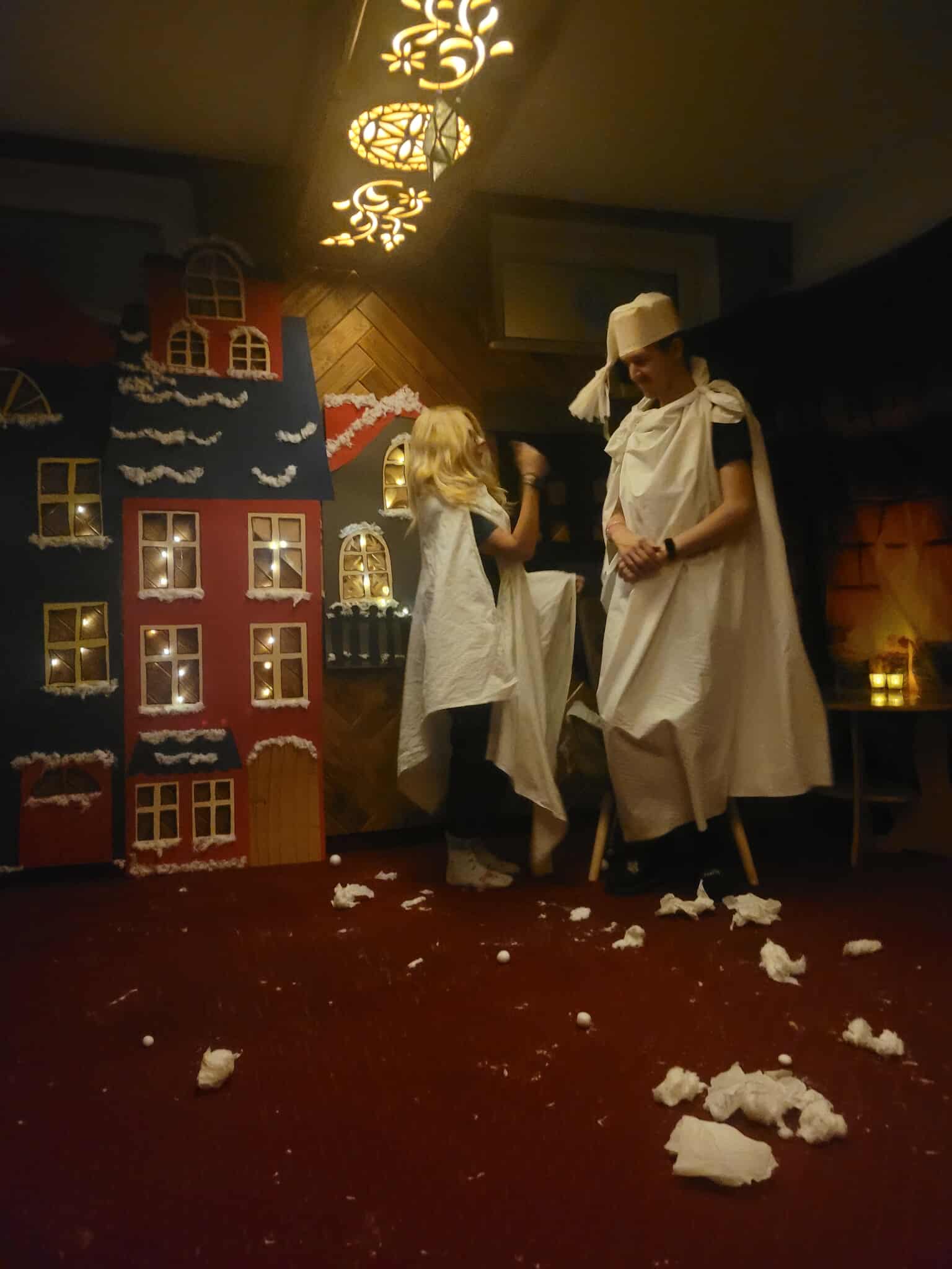 Na obrazku widać: dwie osoby, makiety domów