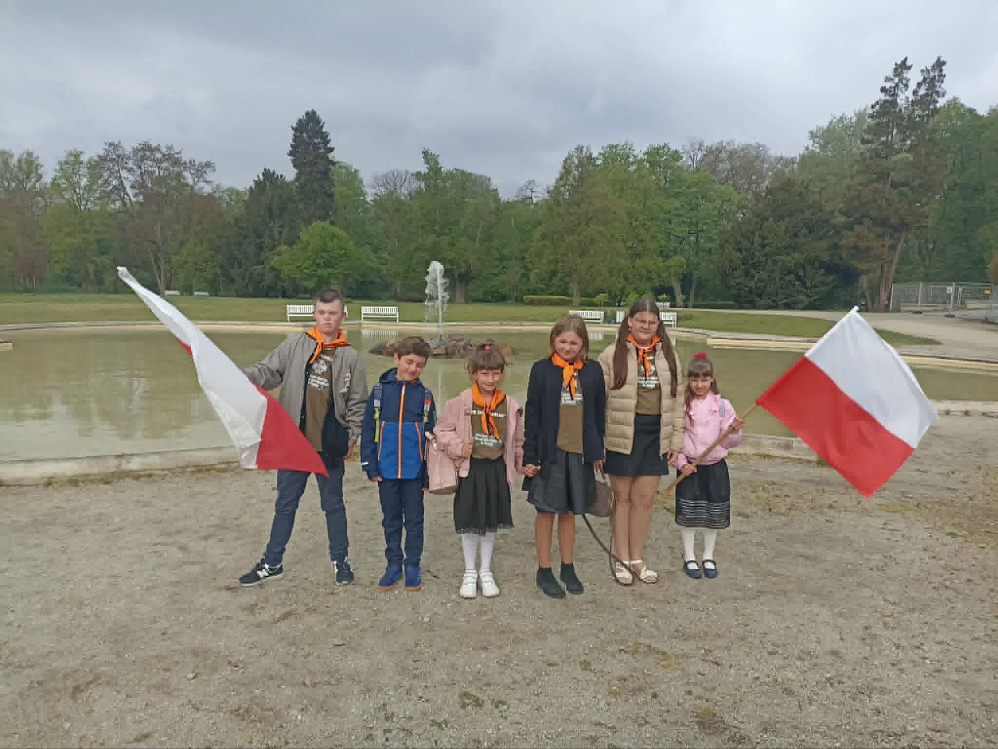 Na obrazku widać: grupę osób, flagi biało- czerwone