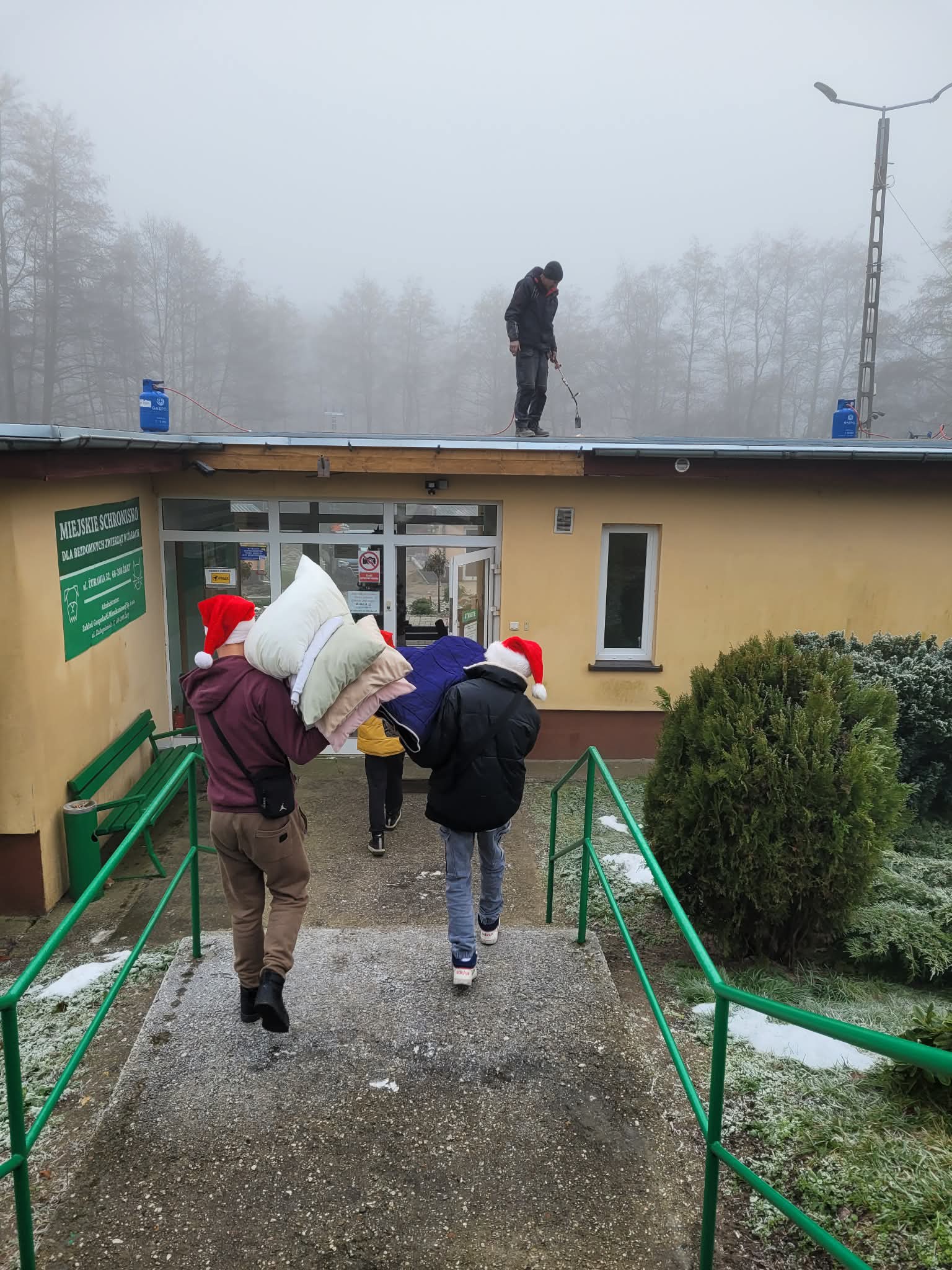 Na obrazku widać: dwie osoby, budynek