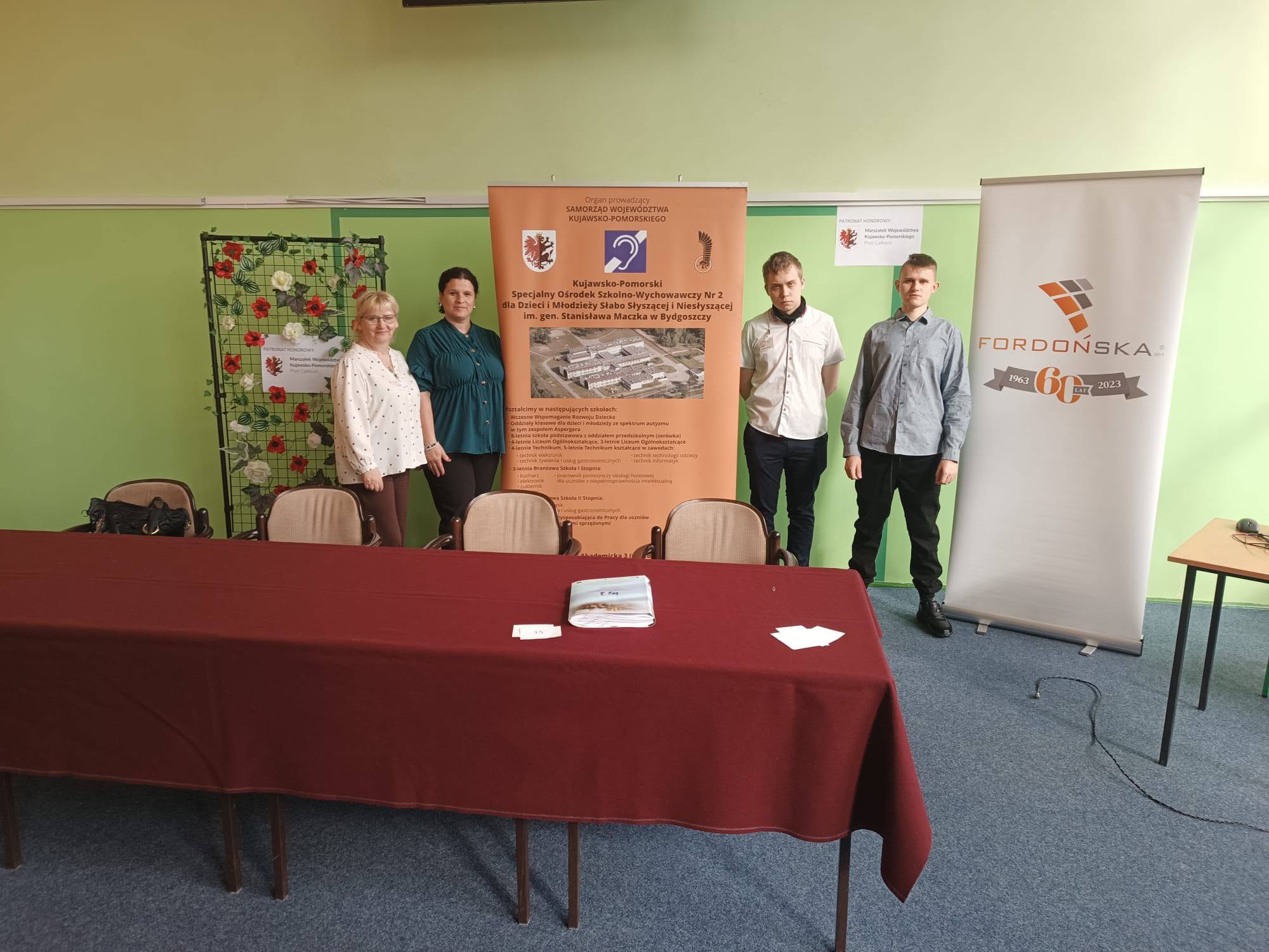 Na obrazku widać: 4 osoby, stół, 