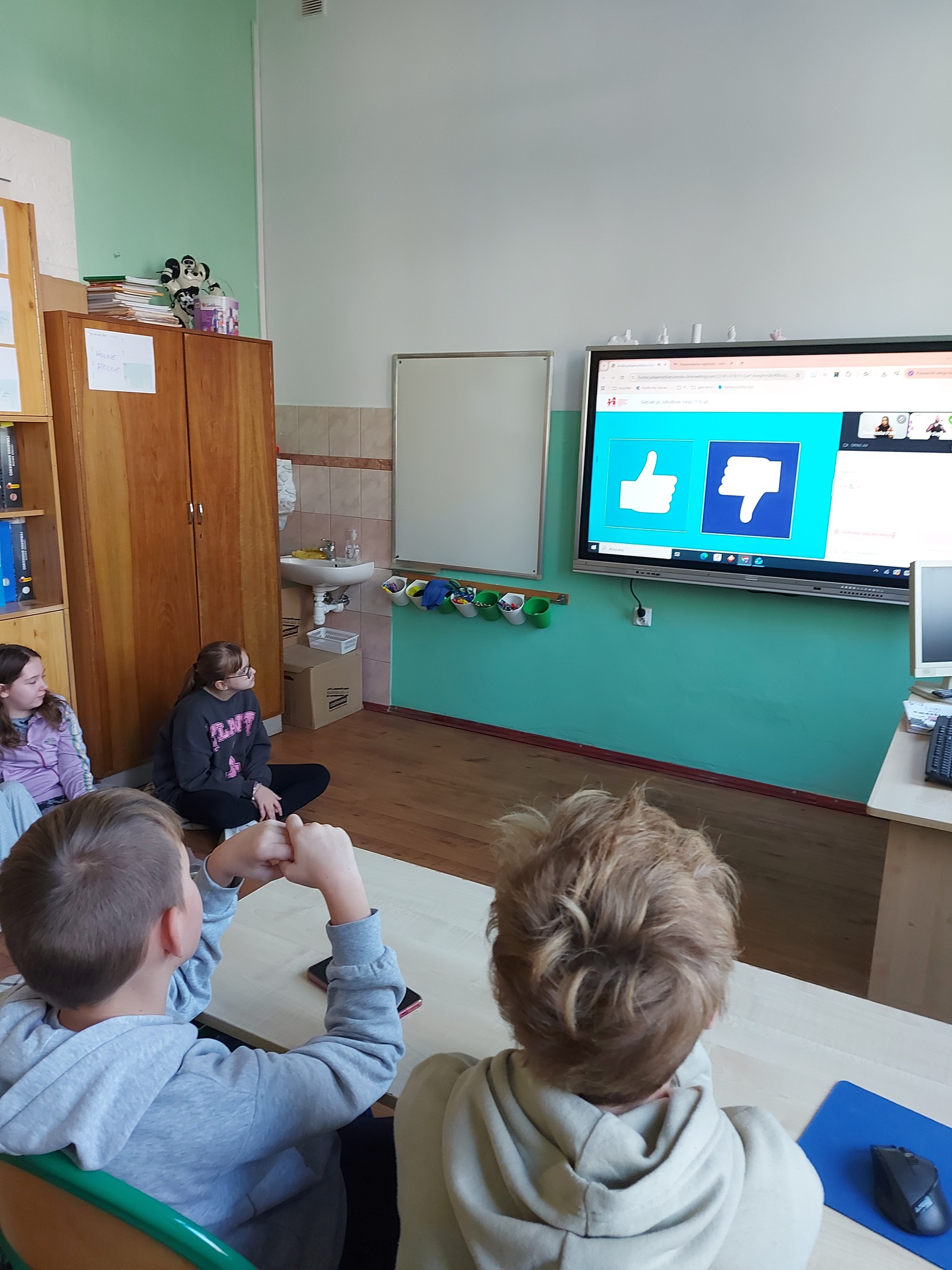 Widać grupę osob, ekran, ścianę 