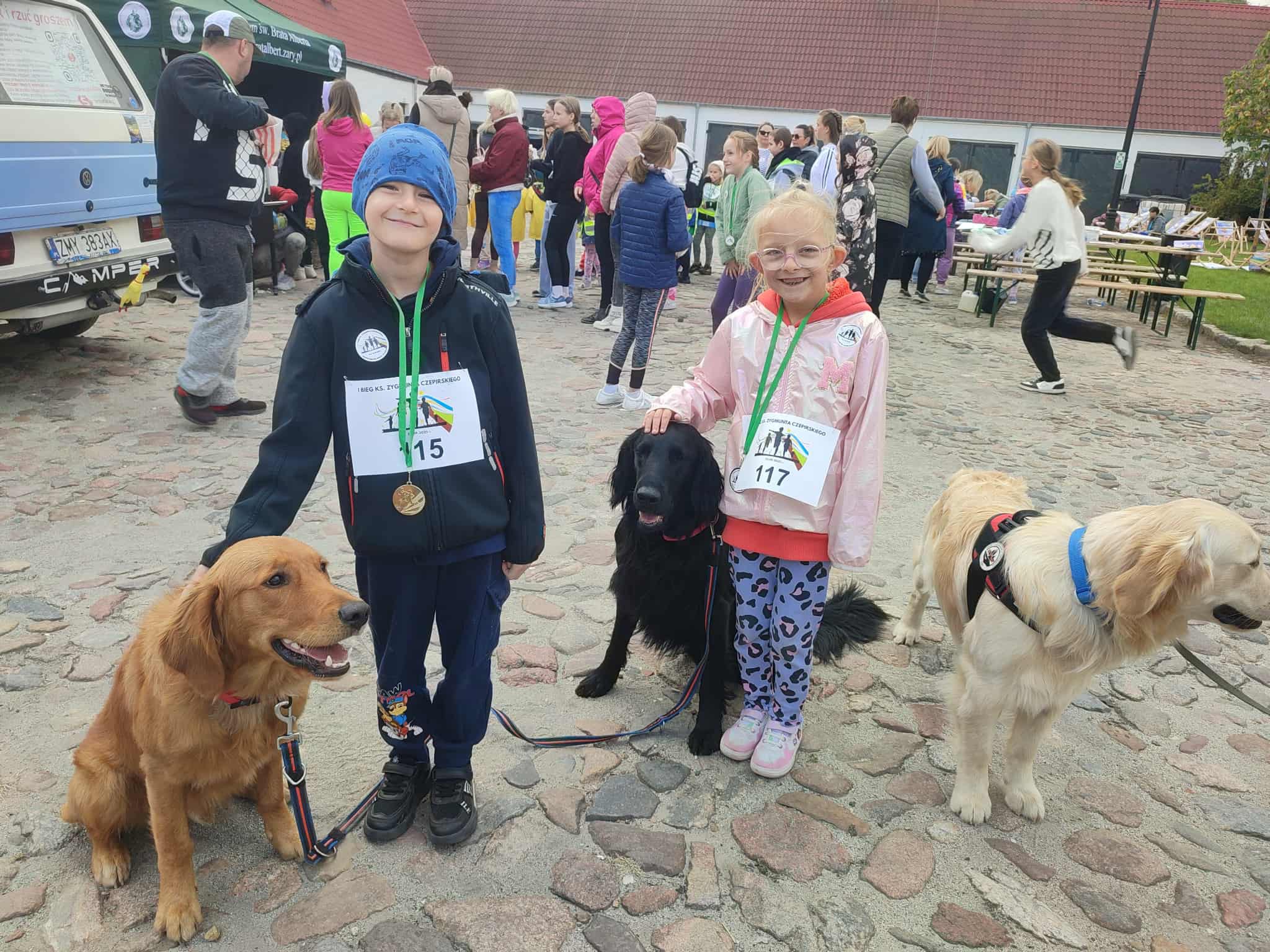 Na obrazku widać: grupę osób, psy