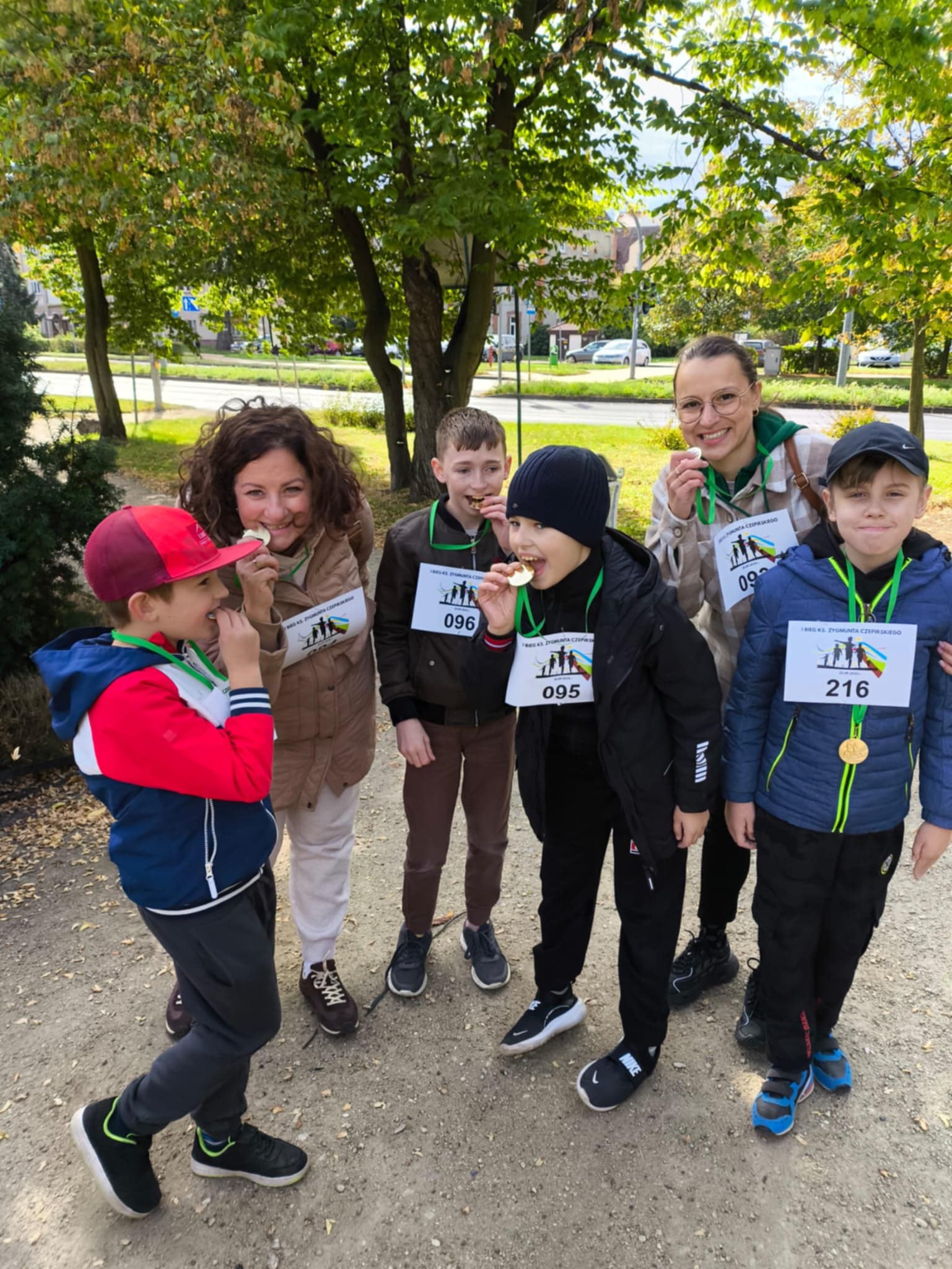 Na obrazku widać: grupę osób, drzewa