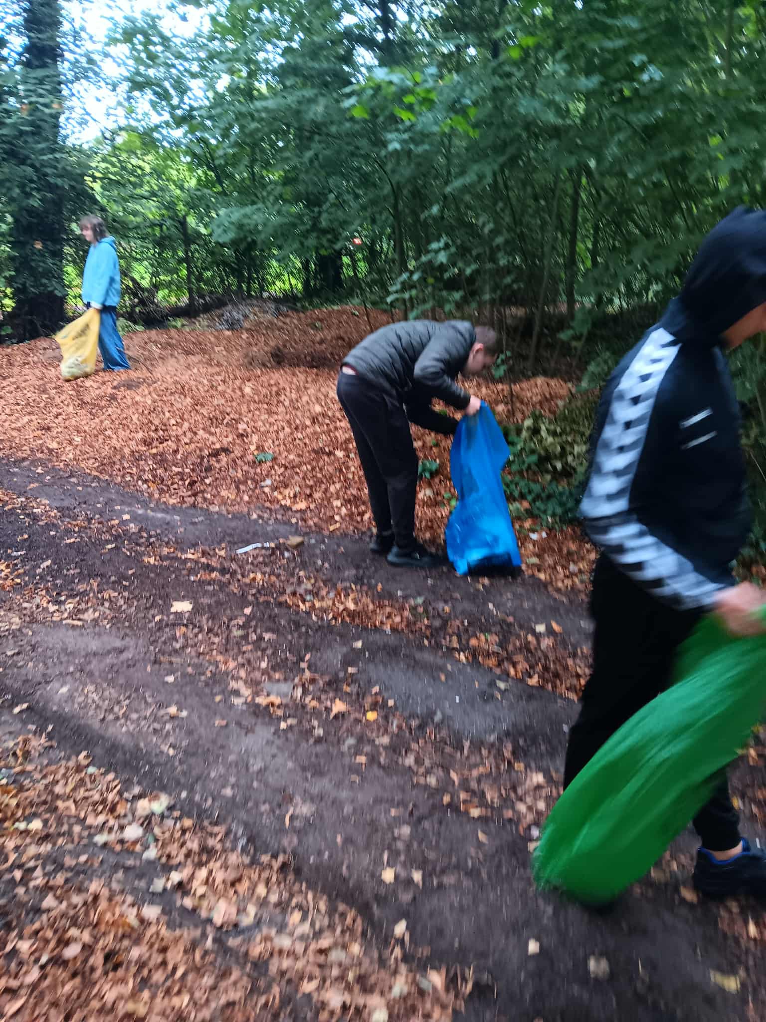 Na obrazku widać: grupę osób, worki, zieleń