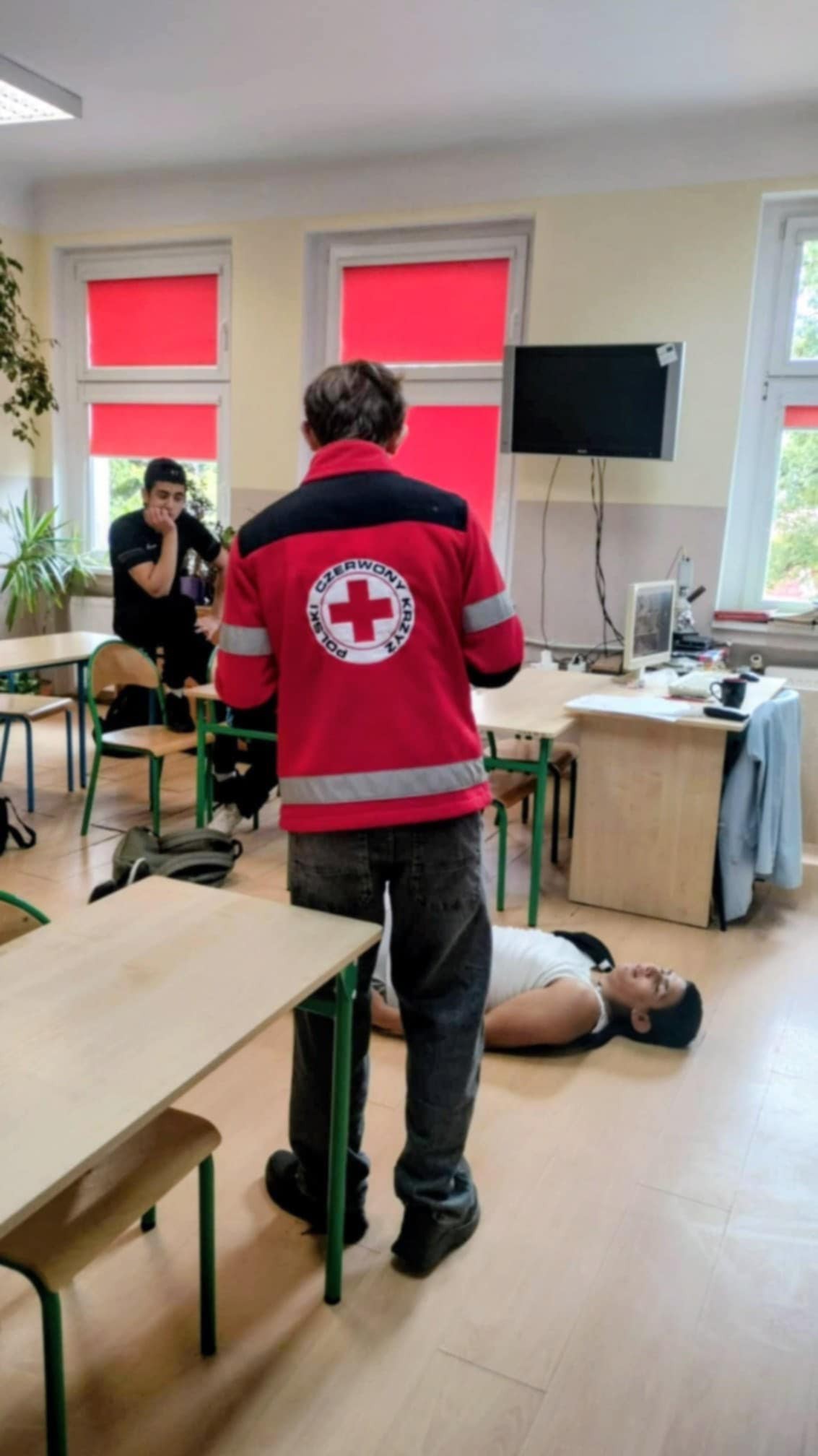 Na obrazku widać grupę osób w pomieszczeniu , ławki