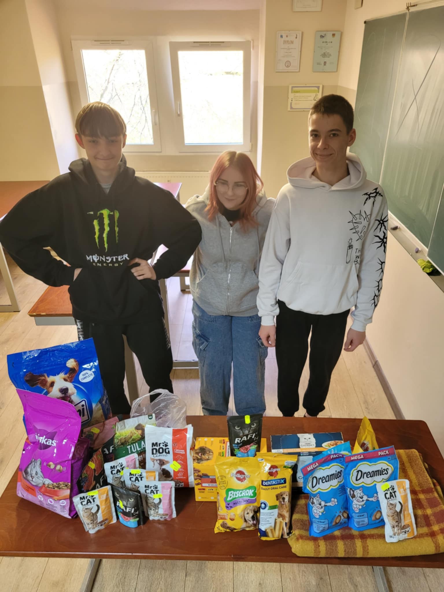 W pomieszczeniu znajdują się trzy osoby, okno, tablica, 